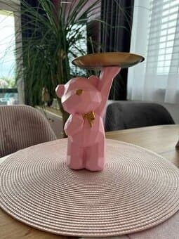 Růžový medvídek z pryskyřice s mašlí a tácem.